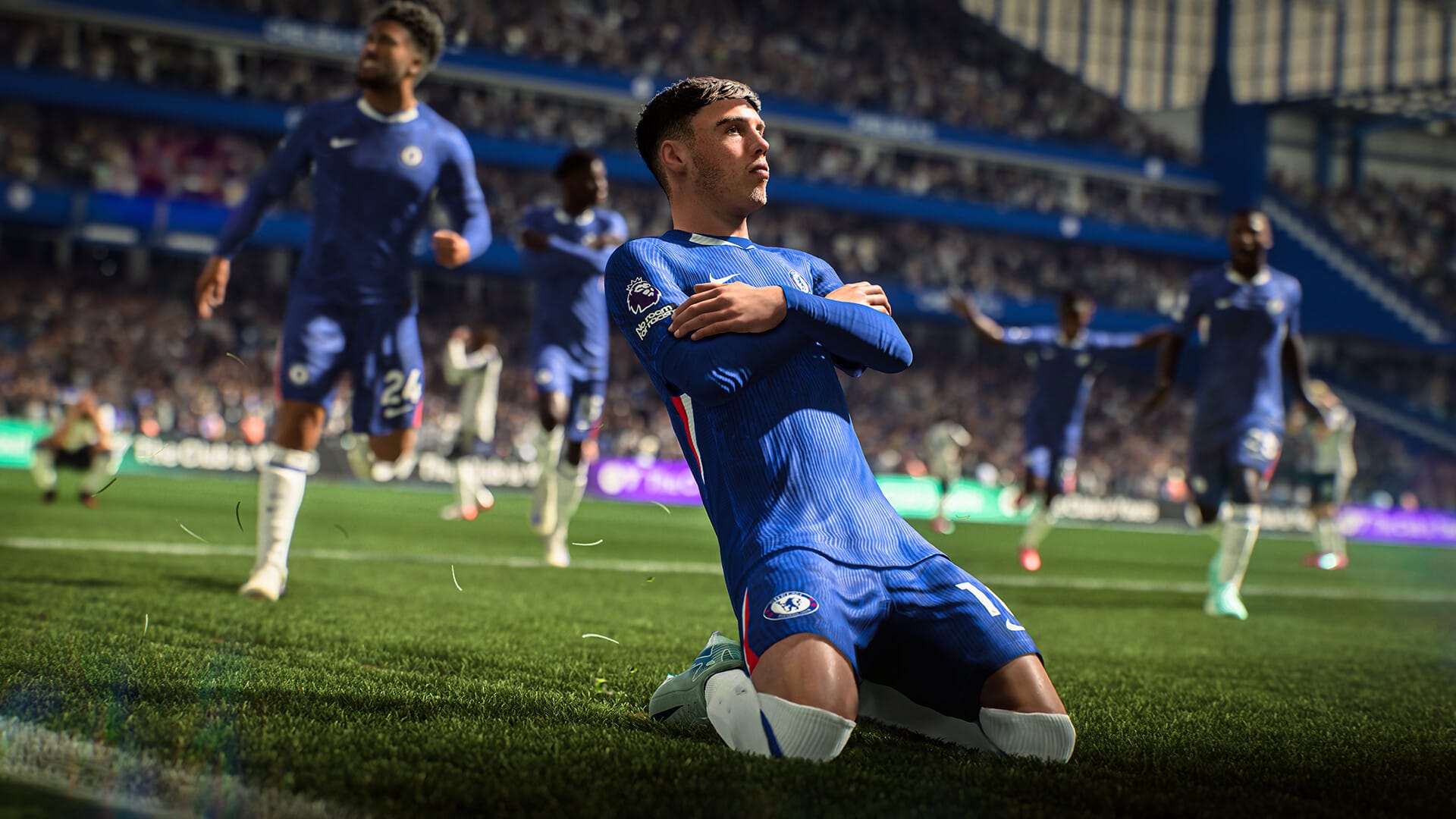 EA Sports FC 26 gameplay showing a Chelsea player sliding on his knees in celebration after scoring a goal, with teammates running towards him in the stadium.